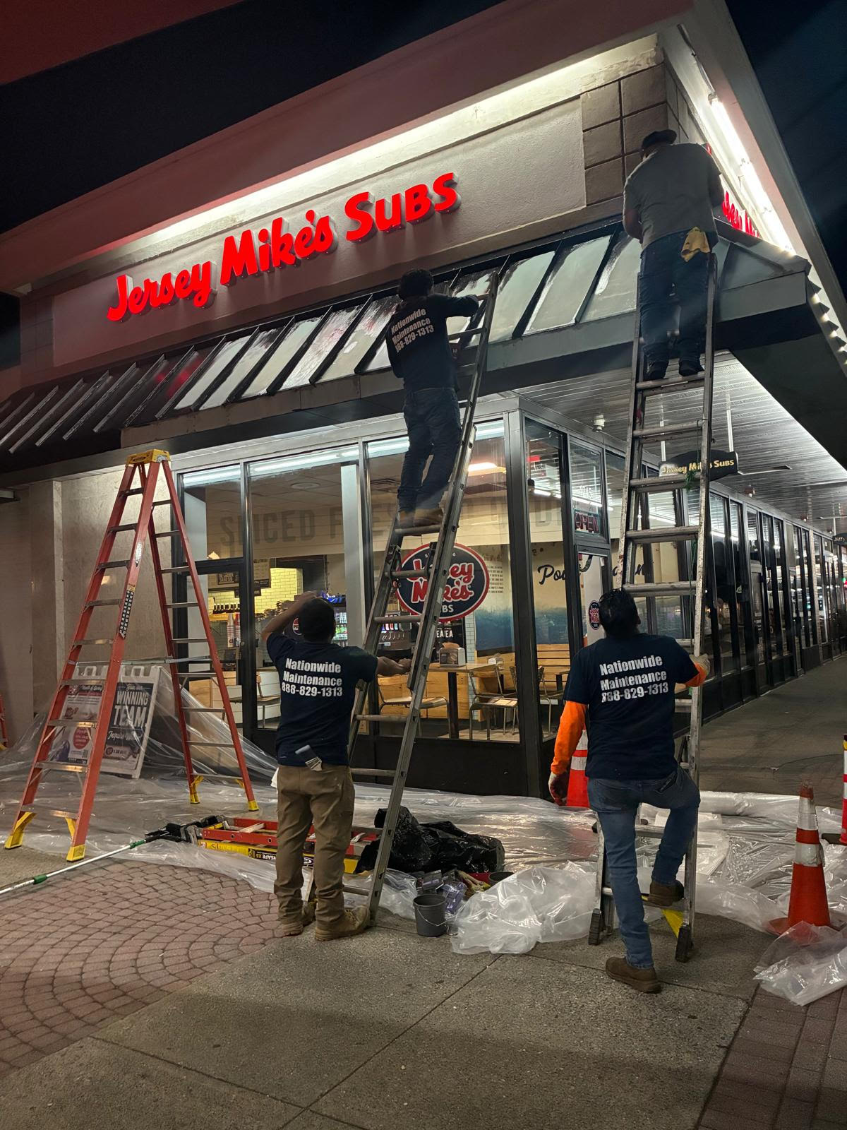 Nationwide Maintenance crew working on Jersey Mike's storefront awning at night