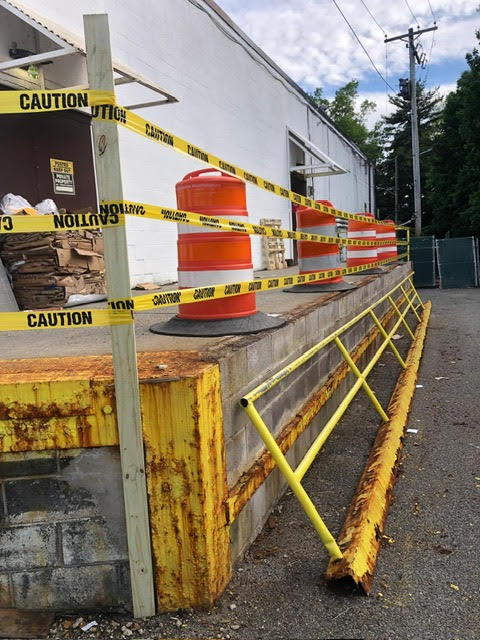 Loading dock with rusted yellow safety railing before repair