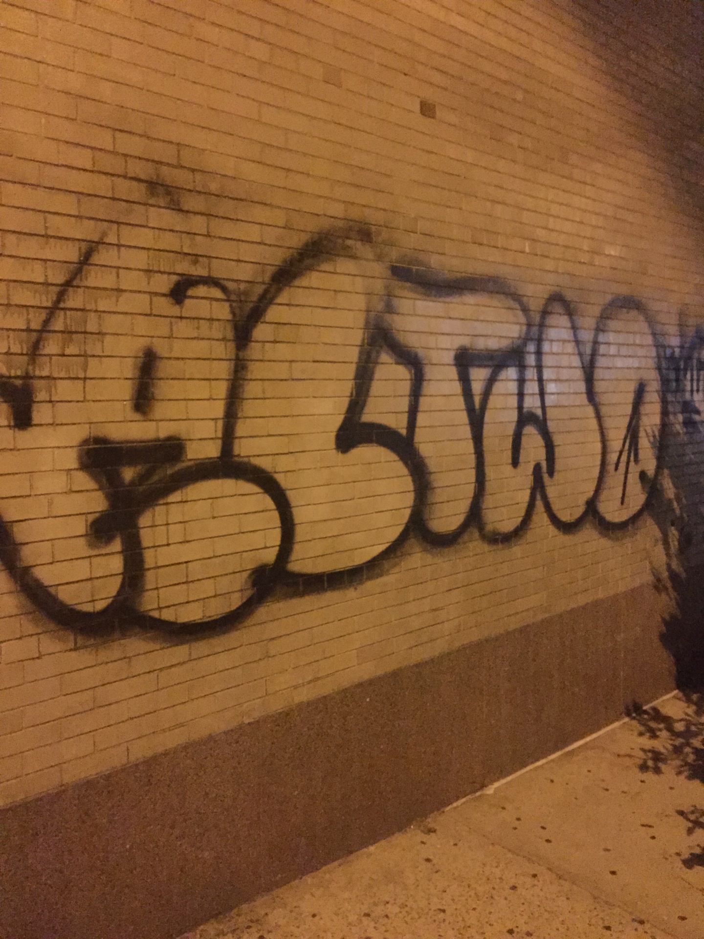 Graffiti tag on brick wall before cleaning