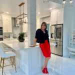 Marcie Manfredonia is wearing a red dress while standing in a white kitchen