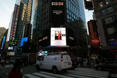A busy Times Square intersection at dusk, with cars and pedestrians. A white van is in the foreground. Digital billboards, including one displaying POWER: Honore, Maura McMahon Schanzer, light up the tall buildings.