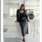 A woman in a black outfit stands smiling in a modern, bright kitchen with white cabinets, gold fixtures, and bar stools. Text promotes kitchen remodeling services by Nationwide Maintenance.