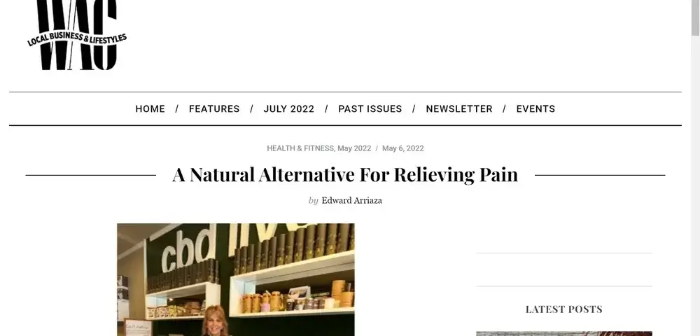 A woman stands and smiles in a shop in front of shelves displaying various CBD products, under a cbd sign. The website header reads WAG: Local Business & Lifestyles. Article title: A Natural Alternative For Relieving Pain.