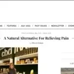 A woman stands and smiles in a shop in front of shelves displaying various CBD products, under a cbd sign. The website header reads WAG: Local Business & Lifestyles. Article title: A Natural Alternative For Relieving Pain.