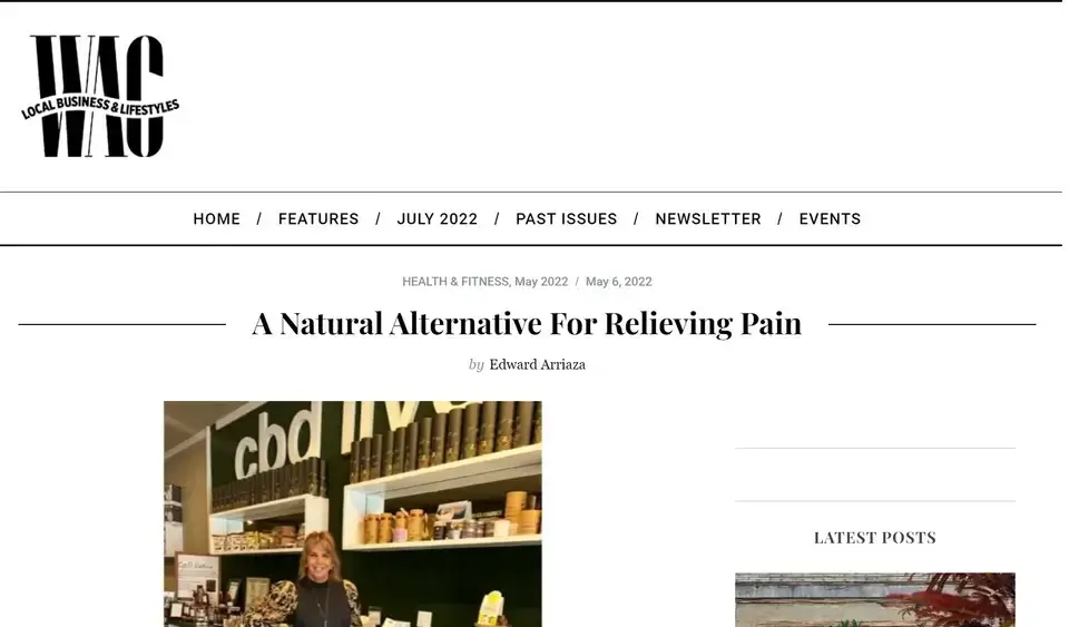 A woman stands and smiles in a shop in front of shelves displaying various CBD products, under a cbd sign. The website header reads WAG: Local Business & Lifestyles. Article title: A Natural Alternative For Relieving Pain.