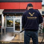 A man wearing a hat and blue jacket holding a hose with a hose.